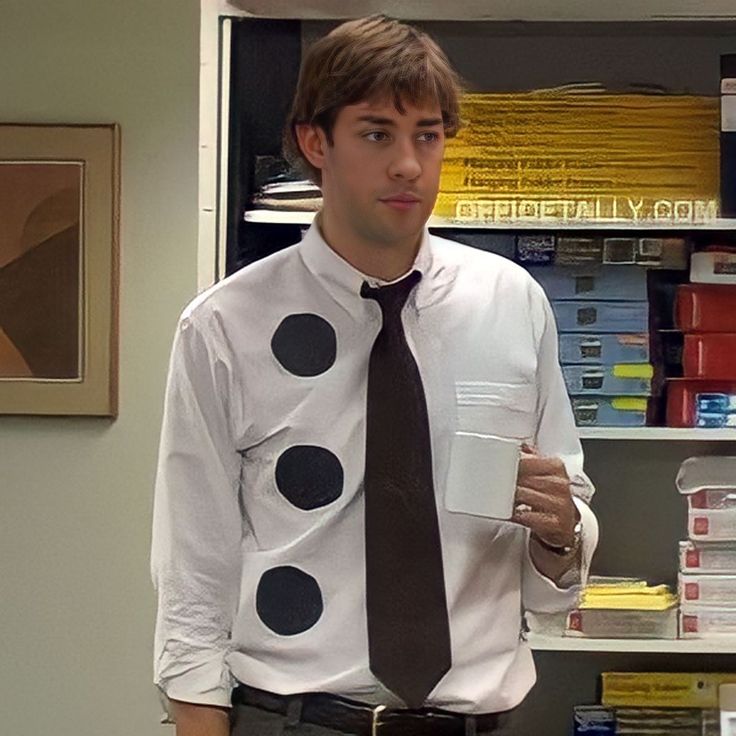 a man in a shirt and tie with polka dots on it, holding a cup