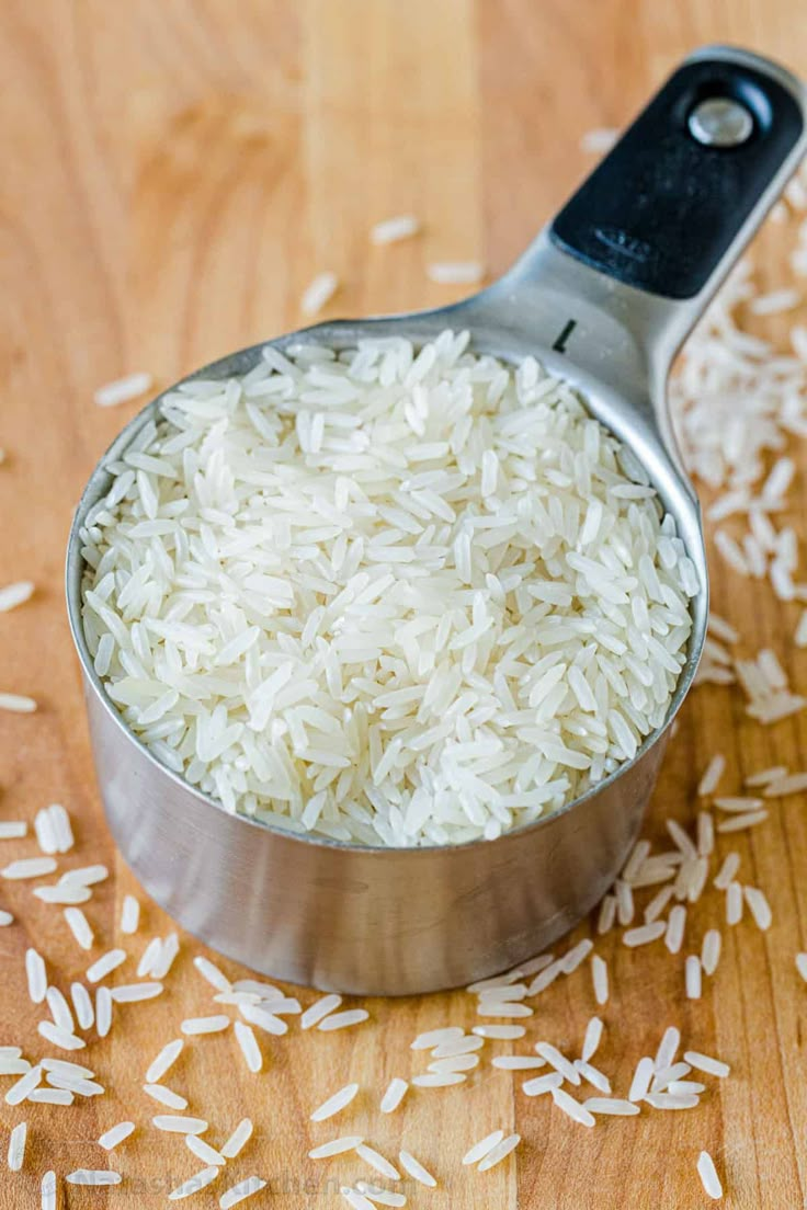 a measuring spoon filled with rice on top of a wooden table