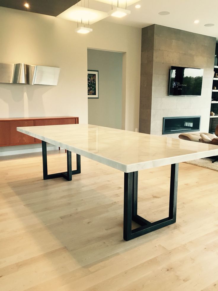 a large white table sitting in the middle of a living room next to a fireplace