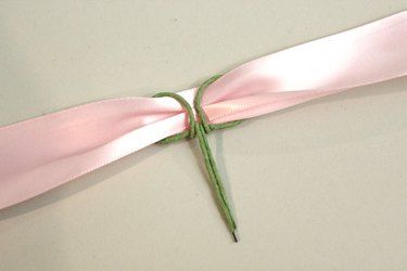 a pink ribbon tied to the side of a white wall with a knot on it