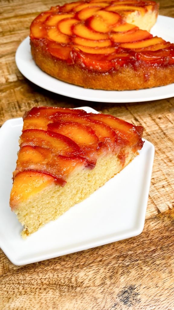 two slices of cake sitting on top of white plates next to each other and one slice has peaches