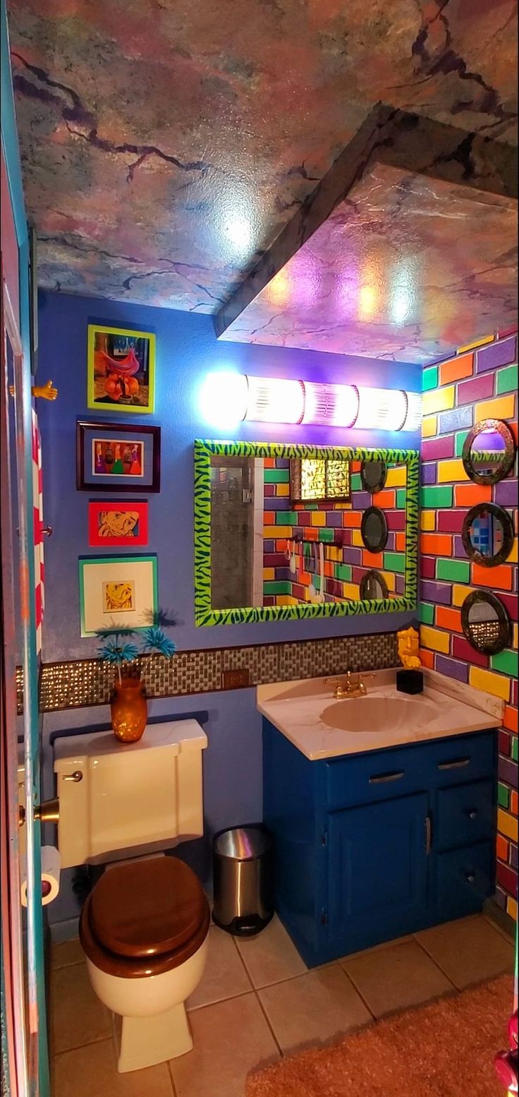 a bathroom with a toilet, sink and colorful tiles on the wall above it's mirror