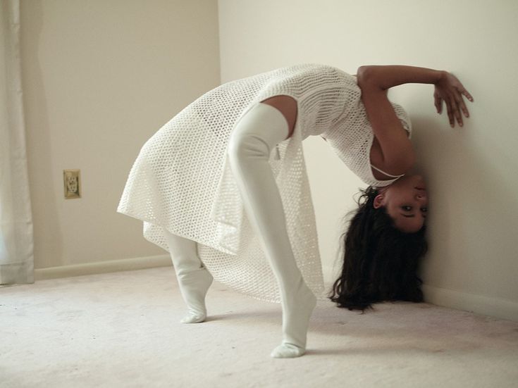 a woman leaning against a wall with her head on the floor and hands behind her back