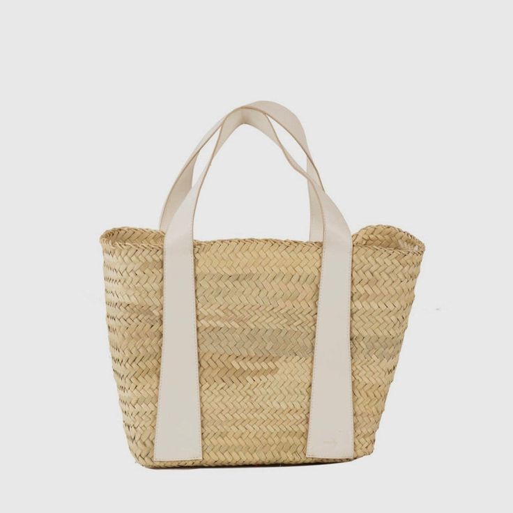 Handcrafted by women in Morocco, the Amira straw handbag boasts impeccable craftsmanship and high quality materials. This lightweight tote is the perfect summer accessory; its rustic touch makes it perfect for strolling at the beach and in the city. Woven from palm leaves, this basket is decorated with white vegan leather detail and comes with an interior zipped and removable canvas pouch. Handwoven in Morocco 100% natural woven palm leaf. Trim: 100% vegan leather Removable canvas pouch with top Chic White Woven Straw Bag, Chic White Straw Bag With Braided Handles, White Natural Fiber Travel Bag, Eco-friendly White Bag With Natural Fiber, Eco-friendly White Bag In Natural Fiber, Natural Straw Bag With Bamboo Handle For Vacation, Summer Natural Straw Bag With Bamboo Handle, Summer Straw Bag With Rolled Handles For Everyday, White Bags In Natural Fiber For Vacation