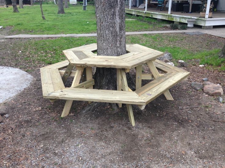 a wooden picnic table sitting under a tree