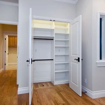 an empty room with open closet doors and hard wood flooring on the hardwood floors