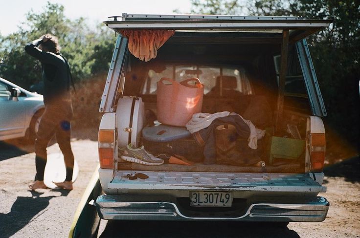 the back end of a van with items in it and two people standing next to it