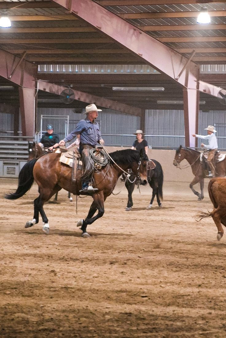 several people riding horses in an arena with one person on the horse and another man running