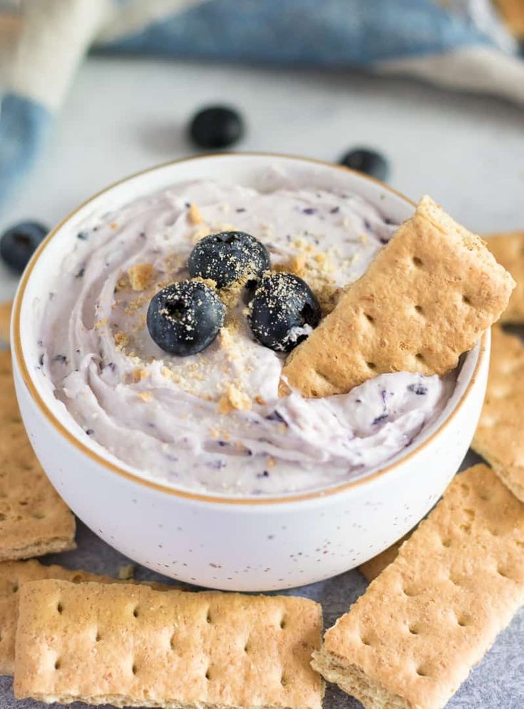 a white bowl filled with blueberry cheese dip surrounded by crackers