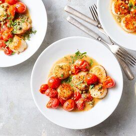 two white plates topped with food next to silverware