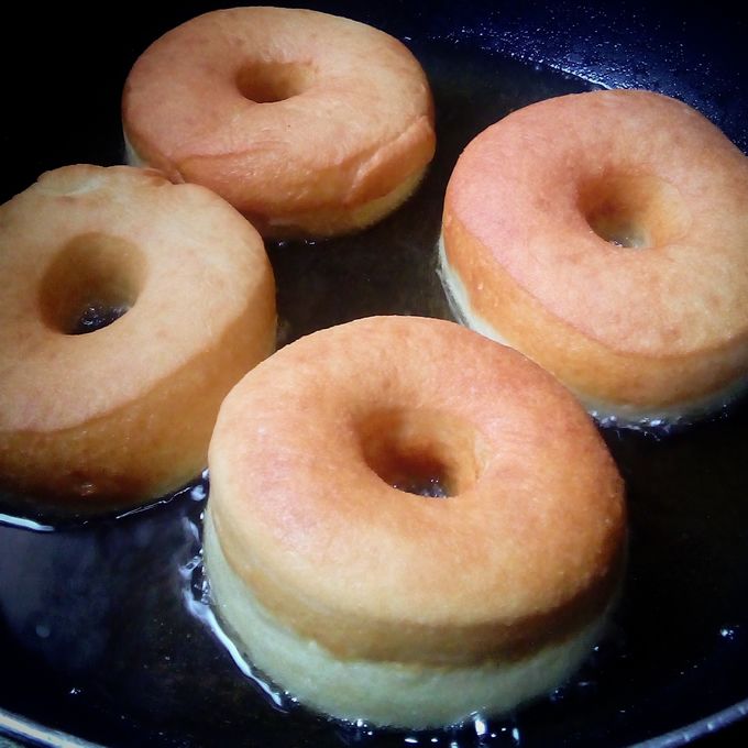 four doughnuts frying in a pan on the stove