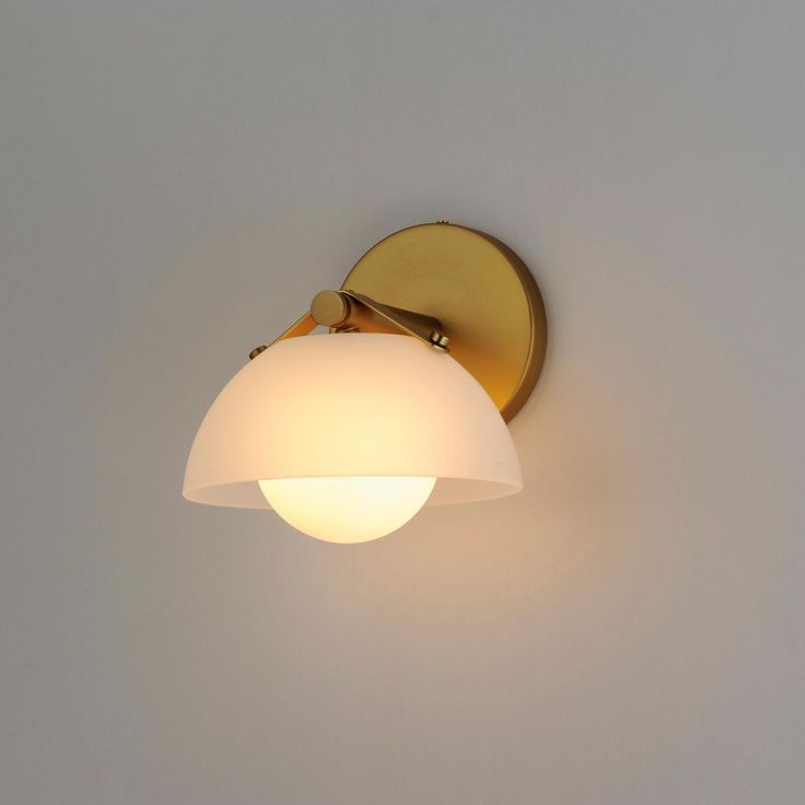 a wall light that is on the side of a wall with a white glass shade