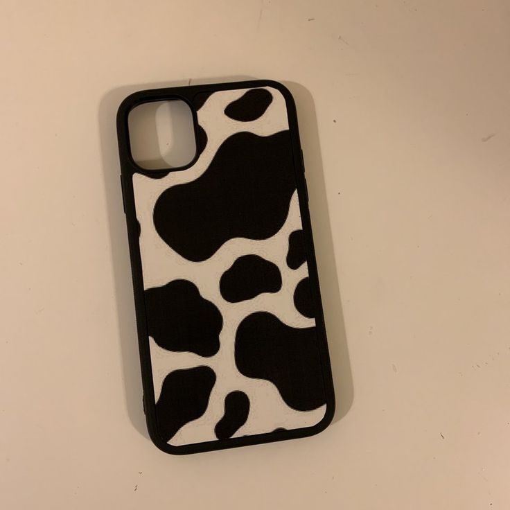 a cell phone case with black and white cow print on it, sitting on a table