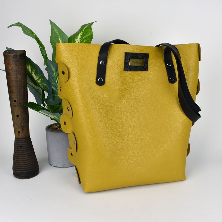 What a gorgeous mustard yellow purse/tote bag! This purse is made with 100% leather and is put together totally with rivets. The black straps are also oil tanned leather. The inside is not lined and that gives this tote that really cool look. Very roomy! The bottom of the purse has metal purse feet. Also, available in a light-colored leather with ostrich print. Size: 13” tall x 13” wide x 5” deep [33cm x 33cm x 13cm] Colors on the screen are as true as possible. Please realize that all monitors Modern Yellow Satchel With Large Capacity, Trendy Gold Leather Bucket Bag, Leather Bucket Bag With Snap Closure In Tote Shape, Leather Tote Bucket Bag With Snap Closure, Leather Bucket Bag Tote With Snap Closure, Chic Yellow Bags With Leather Lining, Trendy Tote Shoulder Bag With Gunmetal Hardware, Leather Bucket Bag With Snap Closure For Shopping, Trendy Leather Satchel With Snap Closure