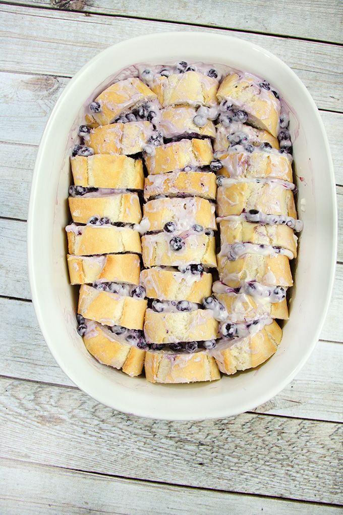 a white bowl filled with blueberry rolls on top of a wooden table