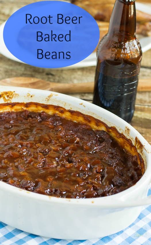 a bowl of baked beans next to a bottle of beer on a table with a checkered cloth