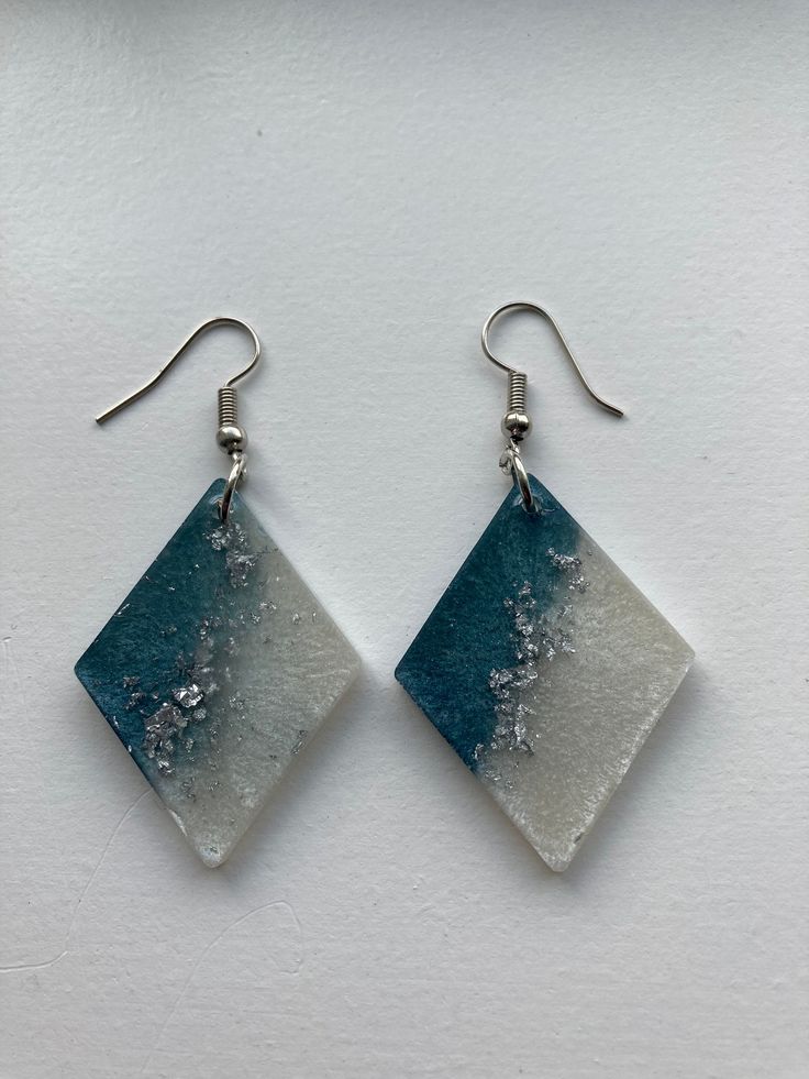 two square shaped earrings with blue and white designs on the front, hanging from silver earwires