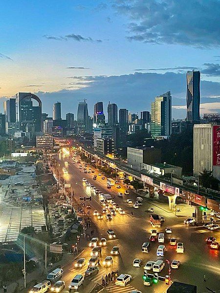 a city street filled with lots of traffic next to tall buildings at dusk or dawn