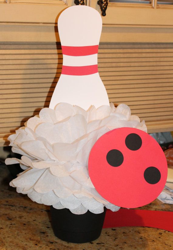 a bowling ball sitting on top of a vase filled with white paper and black polka dots