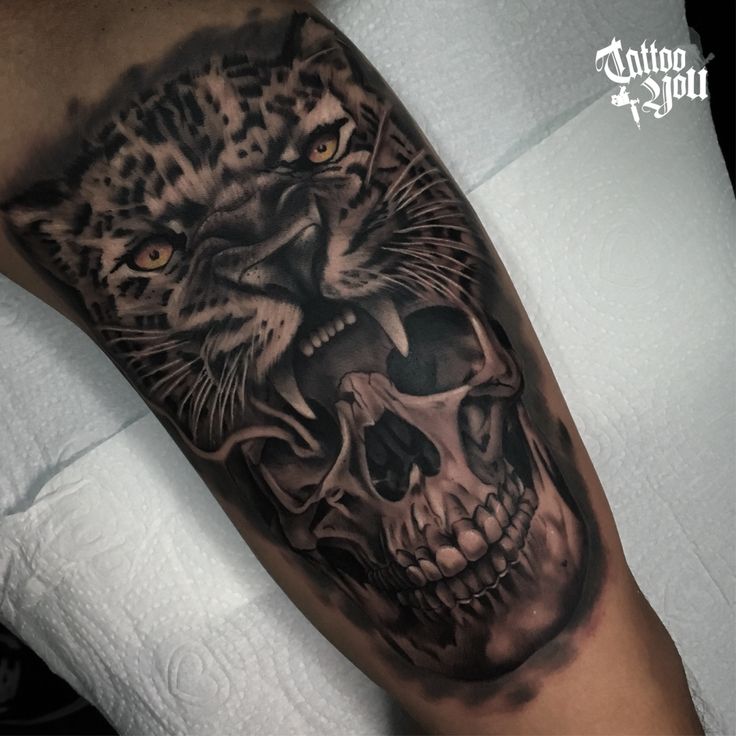 a man's arm with a black and grey tattoo on it, depicting a tiger and a skull