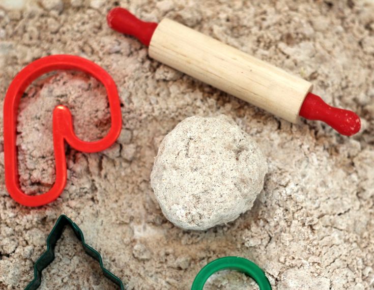 some cookie cutters are laying on the ground next to doughnuts and rolling pin