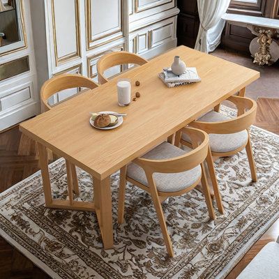 a dining room table with chairs and a rug on the floor in front of it