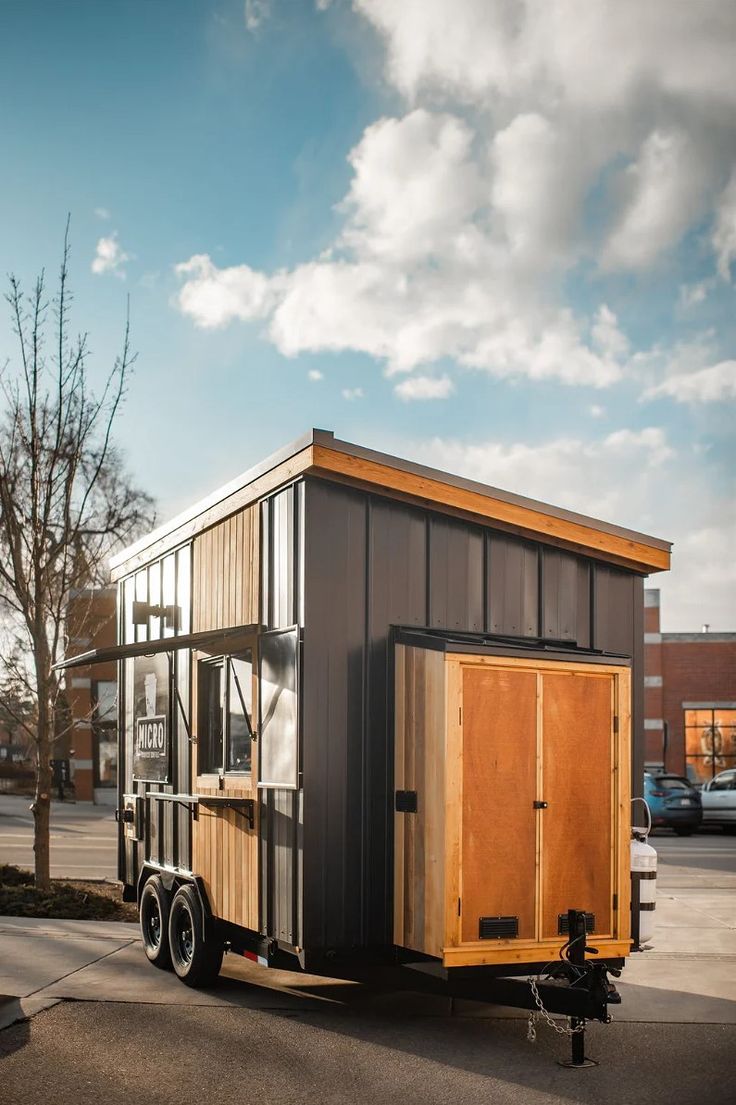 the tiny house is parked on the side of the road in front of a parking lot