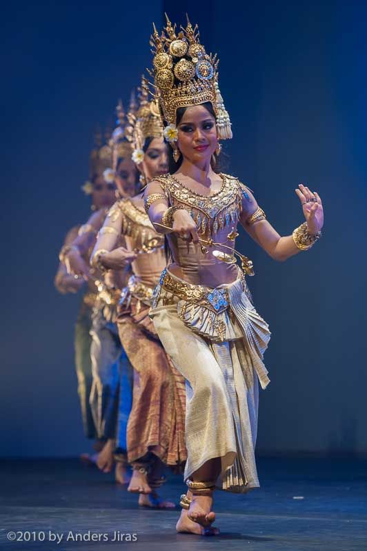 a group of people that are standing on a stage with costumes and headdress