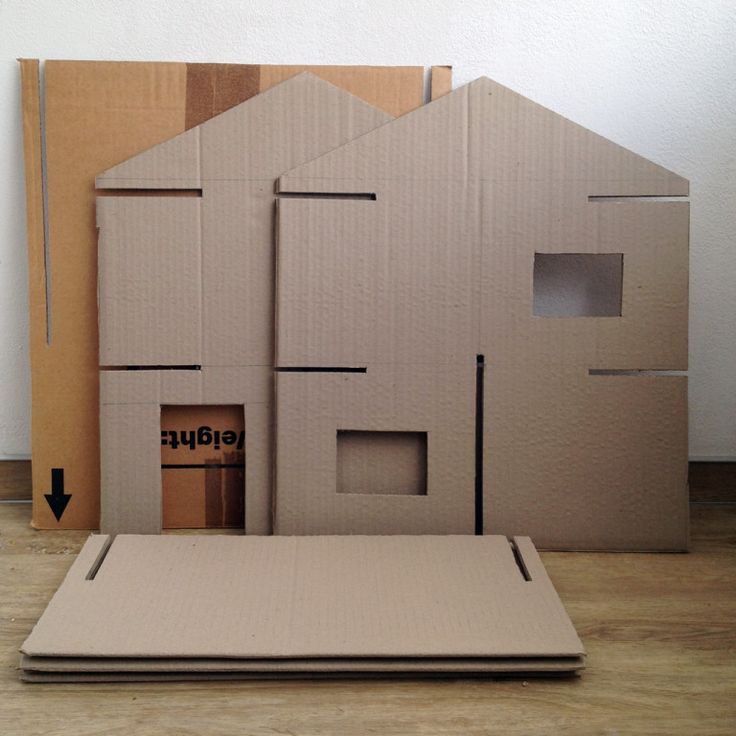 a cardboard house sitting on top of a wooden floor