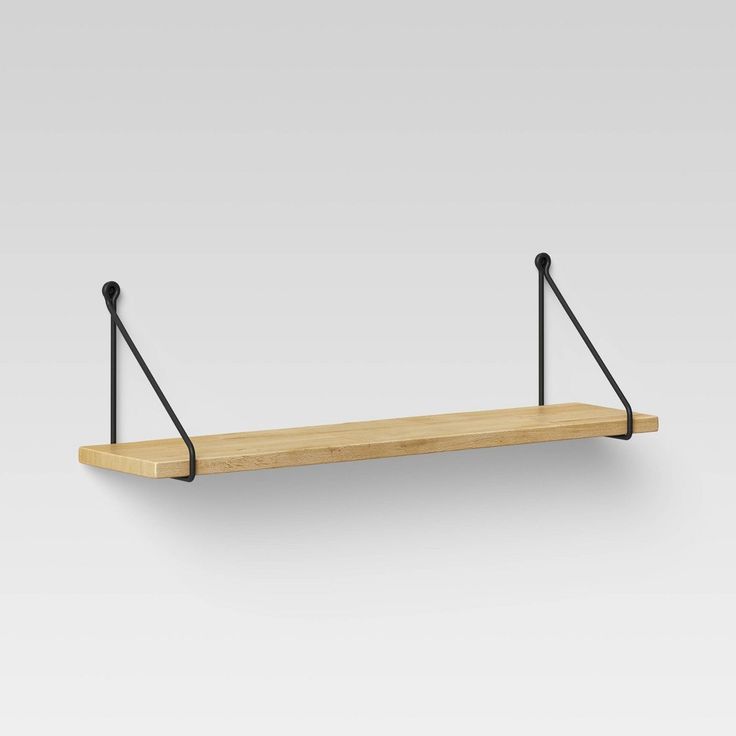 a wooden shelf with two black metal brackets on it and one is hanging from the wall