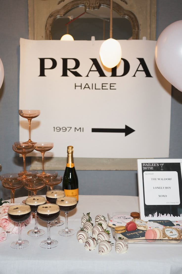 a table topped with champagne and wine glasses next to a sign that reads prada halee