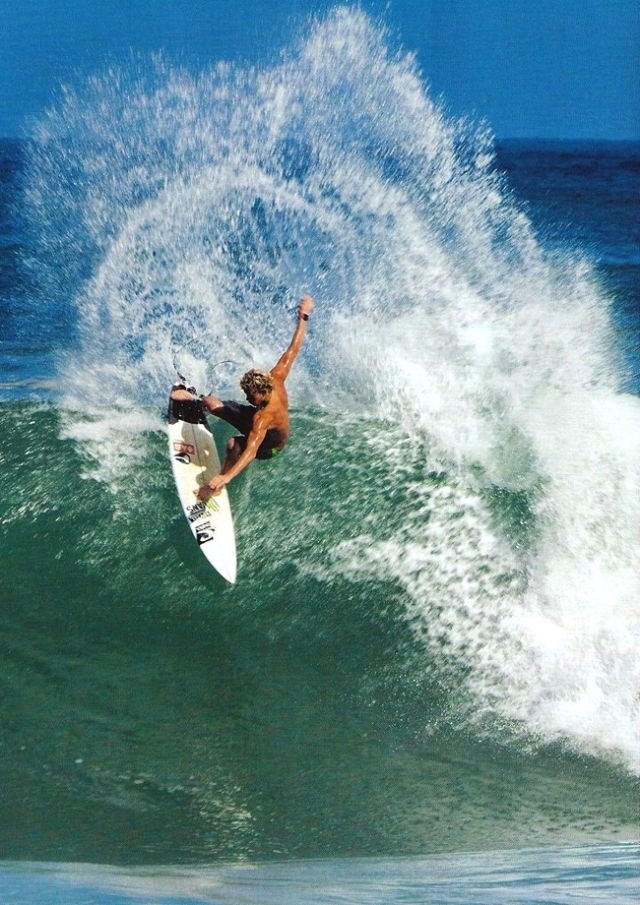 a man riding a surfboard on top of a wave in the ocean with his arms up