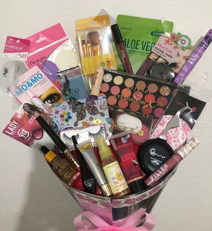 a pink basket filled with lots of different types of cosmetics and makeup products on top of a table