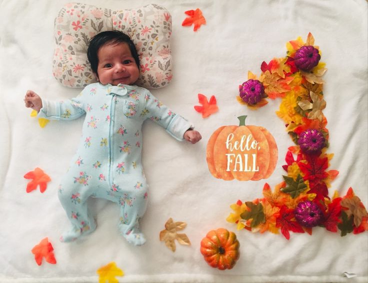 a baby is laying on a blanket with fall decorations