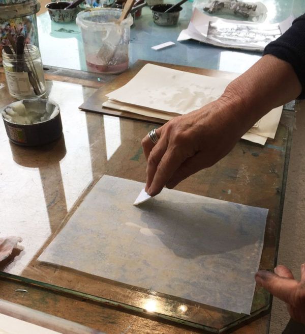 a person is using a brush to paint something on a piece of paper that's sitting on top of a table