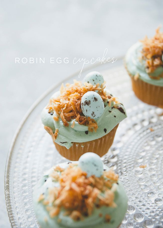 three cupcakes with frosting and sprinkles on a glass plate