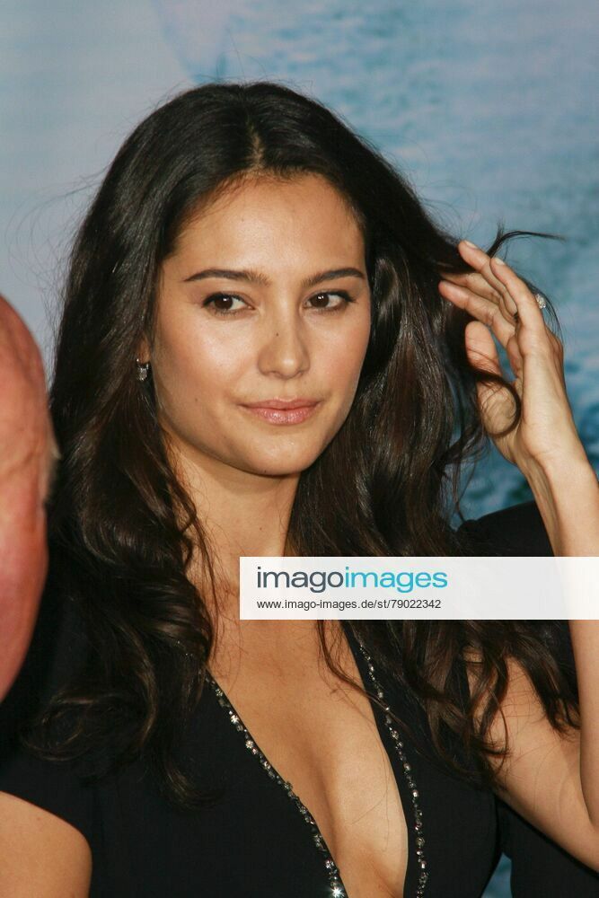 a beautiful young woman in a black dress posing for the camera with her hand on her hair