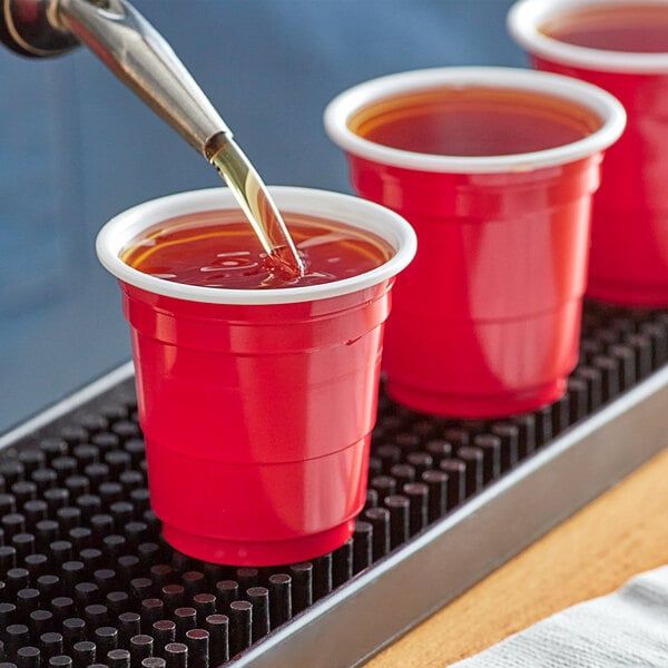 three red cups filled with liquid being poured into them