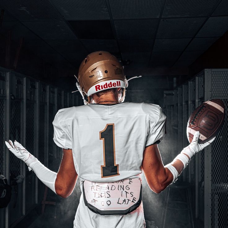 a football player holding a ball in his hand and wearing a helmet with the number 1 on it