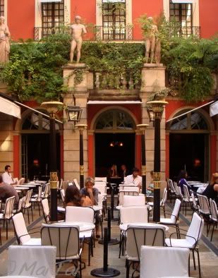 people are sitting at tables outside in front of a building