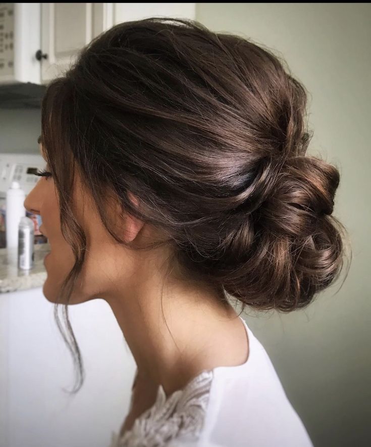 a woman with her hair in a low bun is standing in front of a sink