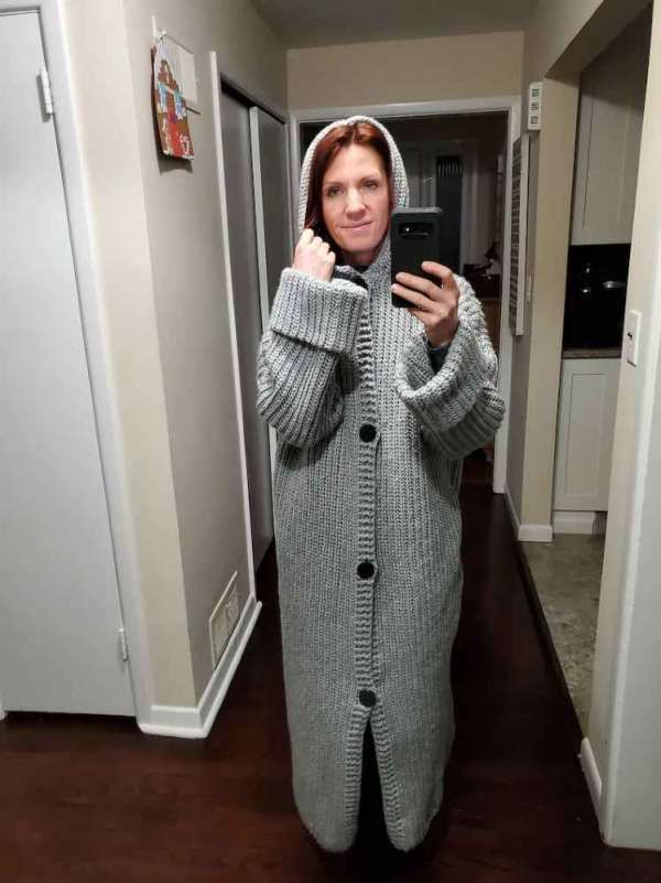 a woman taking a selfie with her cell phone wearing a hooded cardigan sweater