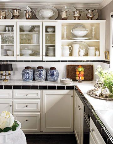 a kitchen filled with lots of white cupboards next to a counter top covered in pots and pans