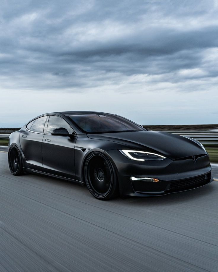 a black tesla car driving down the road