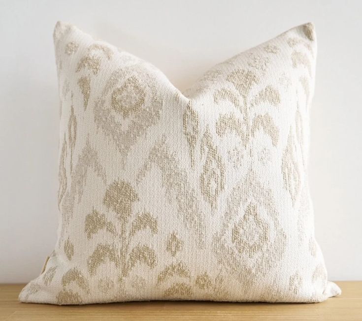 a white and beige pillow sitting on top of a wooden table