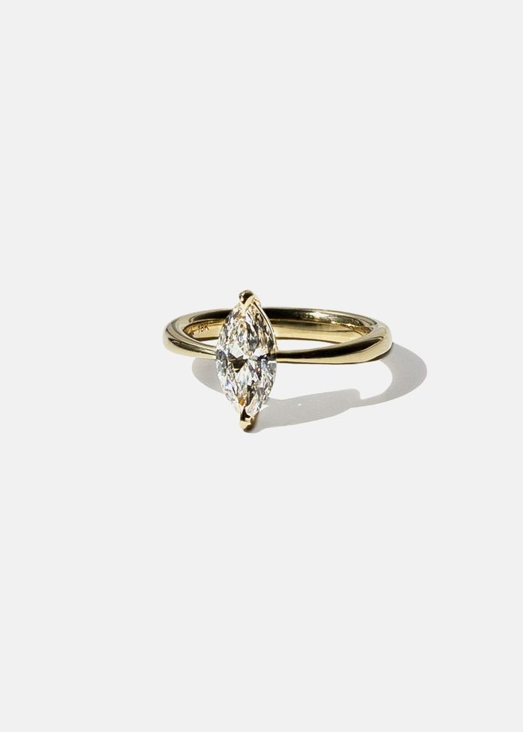 a yellow gold ring with a pear shaped diamond on the top and bottom, set against a white background