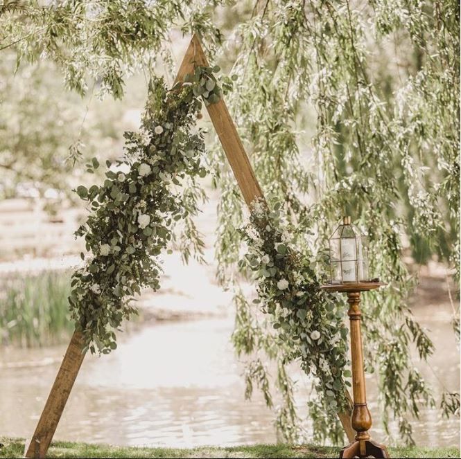 an outdoor ceremony setup with flowers and greenery on the branches, along with candles