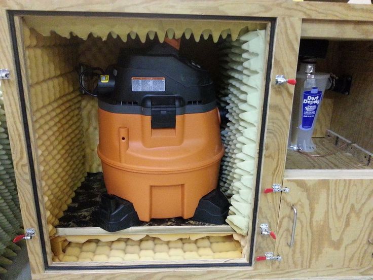 an orange and black vacuum is in a wooden cabinet