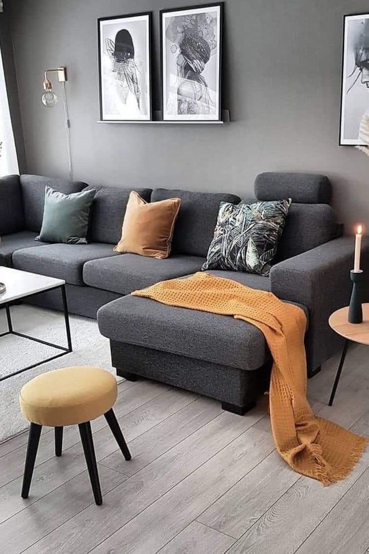 a living room with grey couches and orange throw pillows on top of the sofa