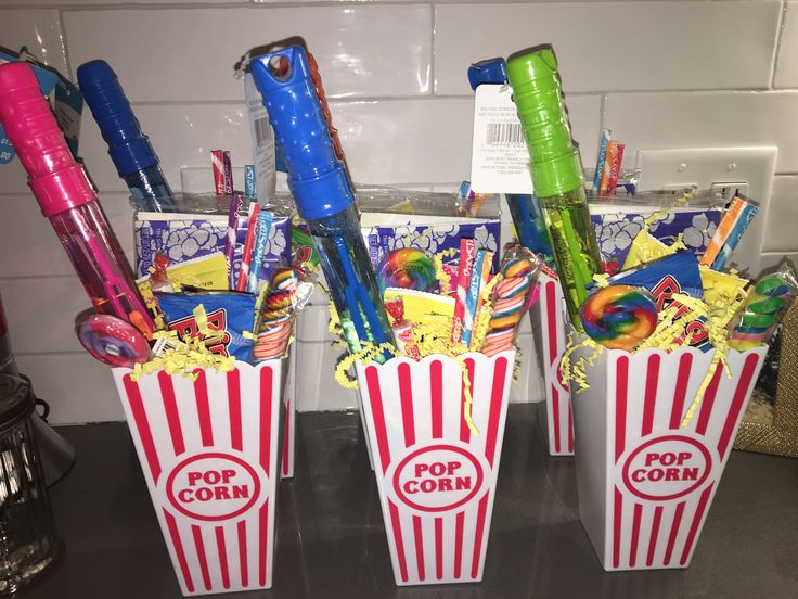 three popcorn buckets filled with candy and confection on top of a counter